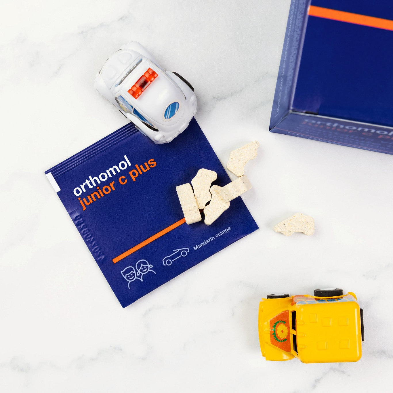 Orthomol junior C Plus package with a toy car and small container on a white surface